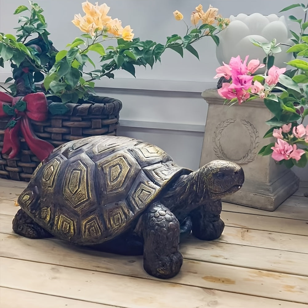 Bronze turtle garden sculpture with dark brown shell and gold accents, on wooden deck surrounded by pink and yellow flowers.