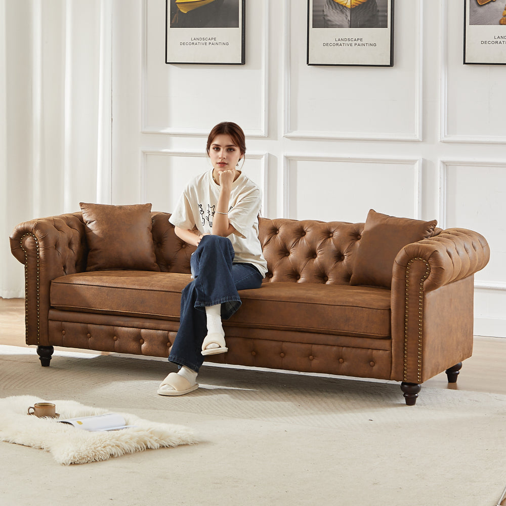 Brown tufted leather sofa with nailhead trim, paired with a cozy living room setup featuring a rug and wall art