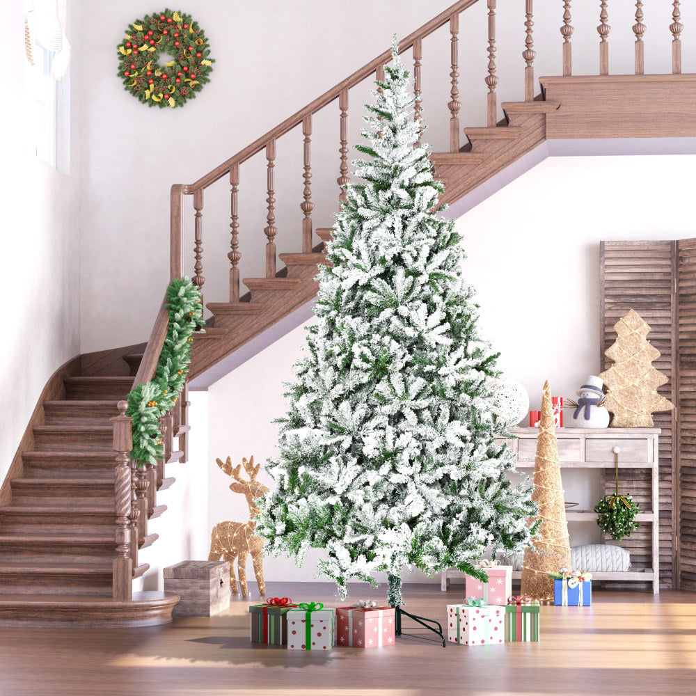 Snow-dusted Christmas tree with wrapped gifts, festive wreath, and holiday decor in a cozy home setting