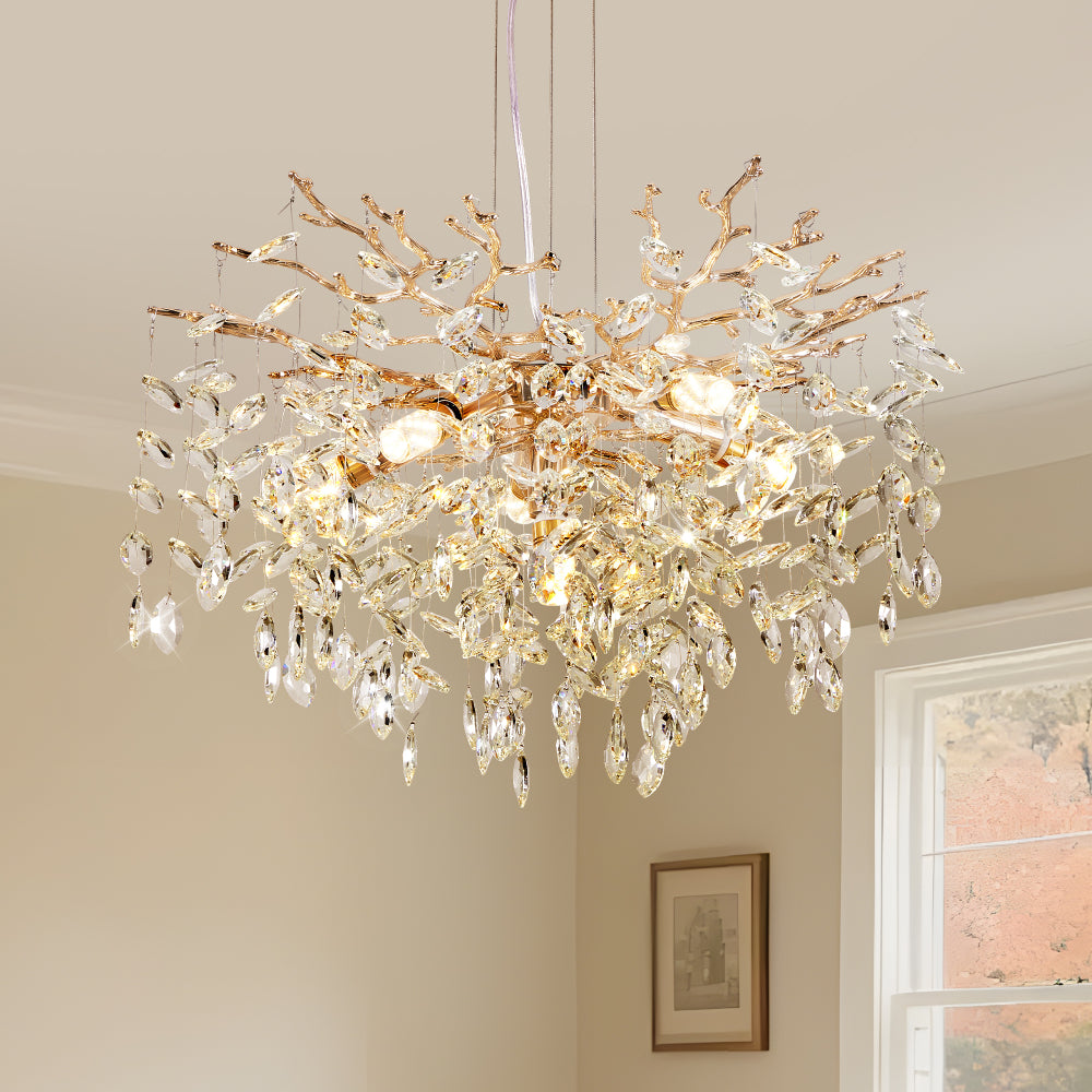 Gold tree branch crystal chandelier with sparkling crystal pendants, illuminated in a modern dining room setting