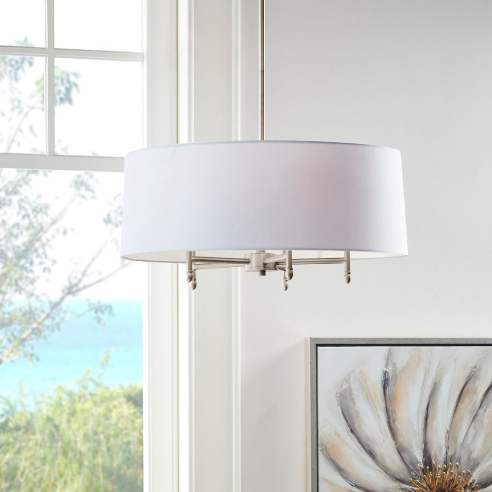 5-light drum shade chandelier with white cotton-linen shade and silver plated brass frame, hanging in bright room with window view of trees and water.