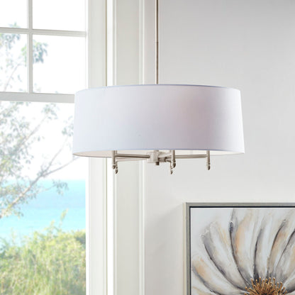 5-light drum shade chandelier with white cotton-linen shade and silver plated brass frame, hanging in bright room with window view of trees and water.