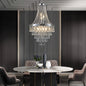 20-inch K9 crystal chandelier with chrome finish, 11 lights, adjustable height 33-71 inches, hanging over a marble dining table in a modern dining room with dark paneled walls and tufted chairs.
