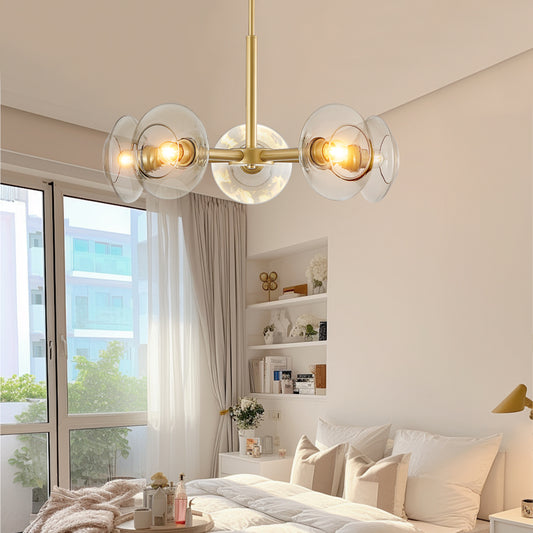 Gold mid-century modern sputnik chandelier with clear glass shades illuminating a bright bedroom with white bedding and large windows.