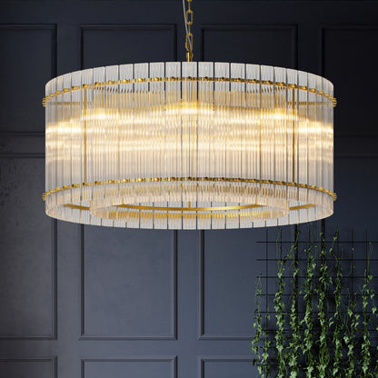 Round Water Ripple Crystal Glass Chandelier with gold trim, illuminated and hanging in a room with dark walls and green plants.
