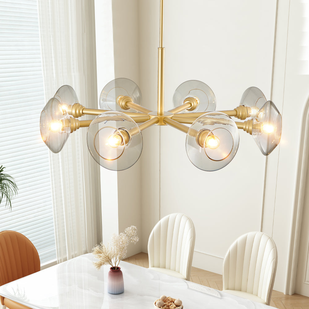 Gold mid-century modern sputnik chandelier with 8 clear glass shades over white dining table with white chairs and dried flowers