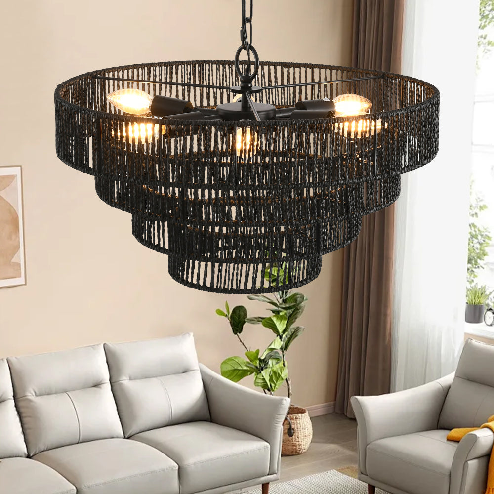 Black hemp rope chandelier with 4-tier design, lit bulbs, hanging in a modern living room with sofa and potted plant.