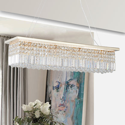 39.4-inch rectangle crystal raindrop chandelier with gold finish, 8-light modern pendant for dining room or kitchen island, hanging in a dining room with gray curtains, white flowers, and abstract painting.