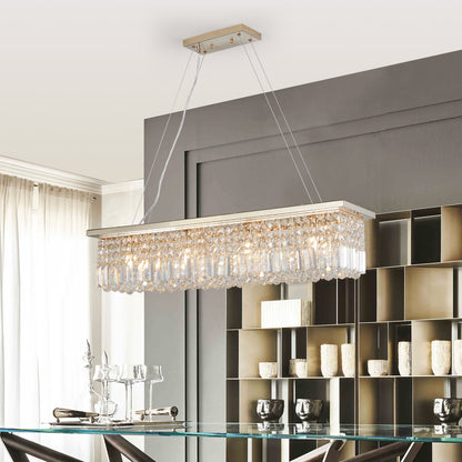 39.4-inch rectangle crystal raindrop chandelier with gold finish, 8-light modern pendant for dining room or kitchen island, hanging over a glass dining table with dark chairs and gray wall shelves.