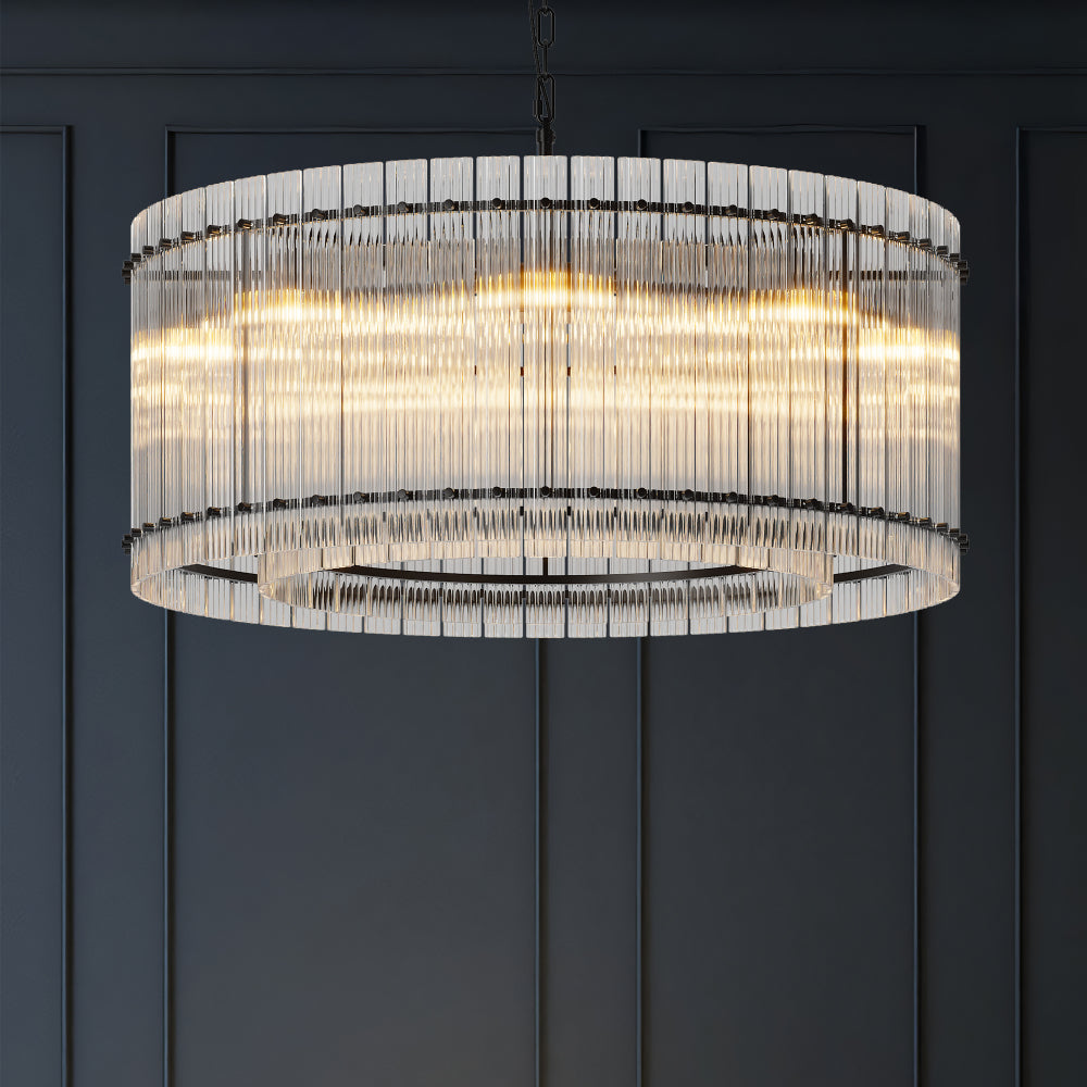 Close-up of modern round black crystal glass chandelier with warm illumination, showcasing layered glass rods against a dark wall.