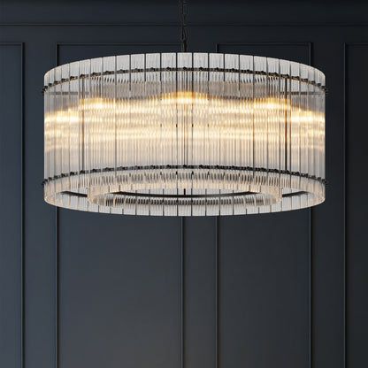 Close-up of modern round black crystal glass chandelier with warm illumination, showcasing layered glass rods against a dark wall.