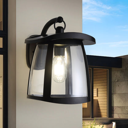 Black solar wall lantern with clear glass shade, mounted on a wall, featuring an exposed bulb and modern design.