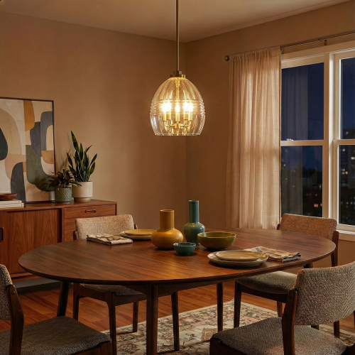 Modern satin brass pendant light with clear glass shade hanging over a wooden dining table in a warm, cozy dining room.