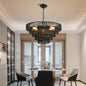 5-tier black hemp rope chandelier with lit E12 bulbs, hanging above a round dining table with modern chairs in a dining room.