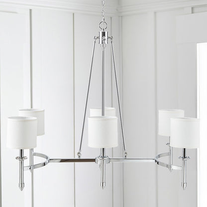 Bedford Collection 6-light chandelier with chrome curved frame and white drum shades hanging in a bright room with white paneling.