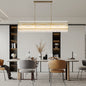 Gold rectangular Water Ripple Crystal Glass Chandelier hanging in bright, modern dining room with white cabinetry.