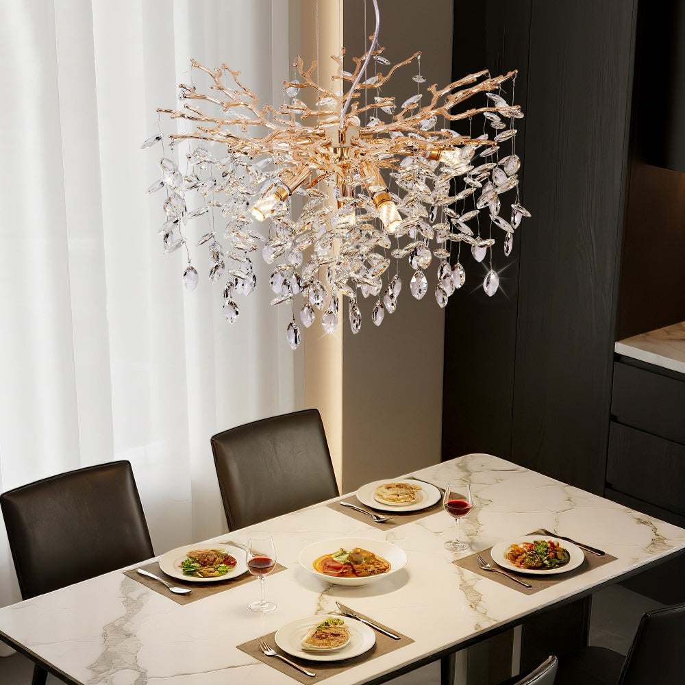 Gold Tree Branch Crystal Chandelier with gold branches and crystal drops, hanging over a marble dining table set with plates and wine glasses.
