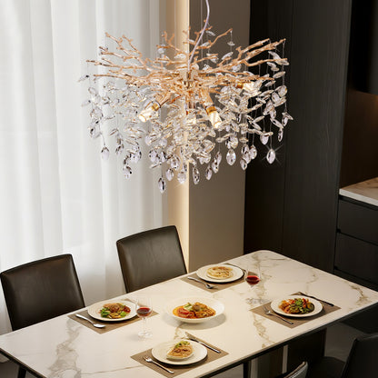 Gold Tree Branch Crystal Chandelier with gold branches and crystal drops, hanging over a marble dining table set with plates and wine glasses.