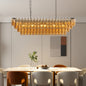 Rectangular tiered chandelier with black metal frame and amber smoke glass, 12-light design, 54" size, above marble dining table.